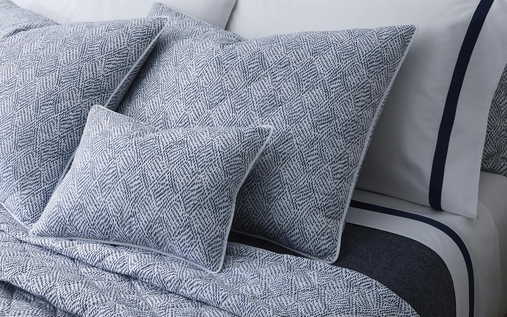 Navy Duma Diamond Bedding Collection by Matouk, featuring Egyptian cotton percale sheets and pillowcases, is elegantly arranged on the bed for a luxurious look.