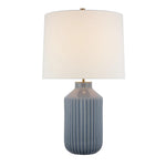 The Braylen Medium Ribbed Table Lamp by Visual Comfort features a ribbed blue ceramic base inspired by dinnerware motifs and is topped with a large white linen shade.