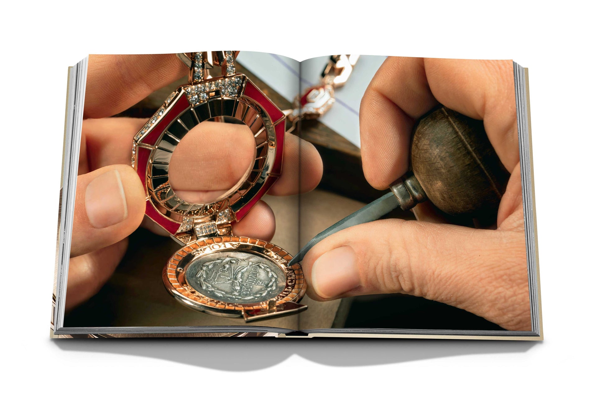A close-up of hands working on an intricate piece of jewelry, examining a coin placed inside a circular and ornate pendant, reminiscent of the craftsmanship seen in Bulgari Beyond Time by Assouline, with tools in the background.