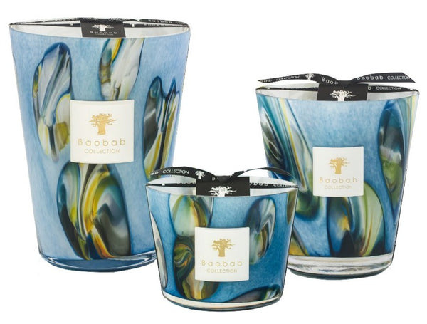 Three decorative Baobab Collection Oceania Tingari candles with swirling blue and yellow patterns on hand-blown glass containers of varying sizes.
