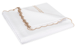 A folded white Matouk Classic Chain Scallop Matelassé blanket from the Dune collection, featuring scalloped beige trim and elegant embroidery along the edge.