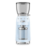 The Smeg Coffee Grinder Collection in light blue features a transparent bean hopper, glass container for ground coffee, and adjustable grinding levels—ideal for use with espresso machines.
