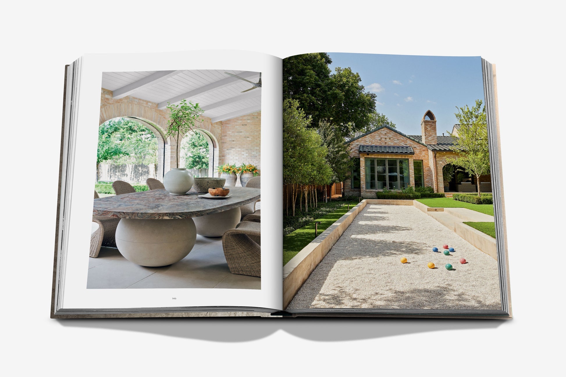Open book from Assouline's "Relaxed Luxury": left page shows a Chad Dorsey dining area with a stone table and arched windows; right page features a landscaped garden, bocce court, and stone house.