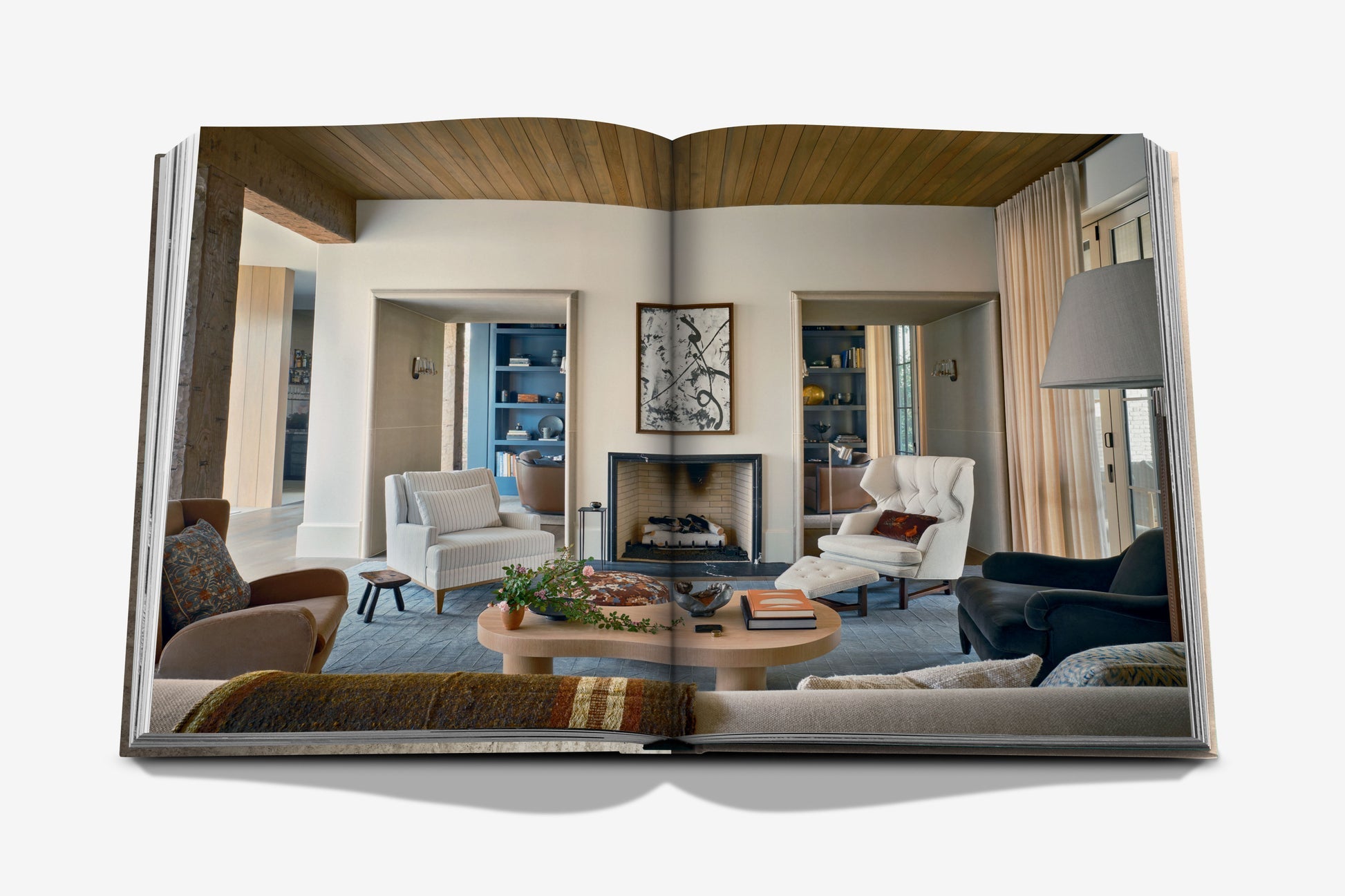 Open to a stunning photo of a modern living room with armchairs, a fireplace, and built-in shelves—“Relaxed Luxury” by Assouline captures Chad Dorsey’s signature laid-back elegance in interior design.