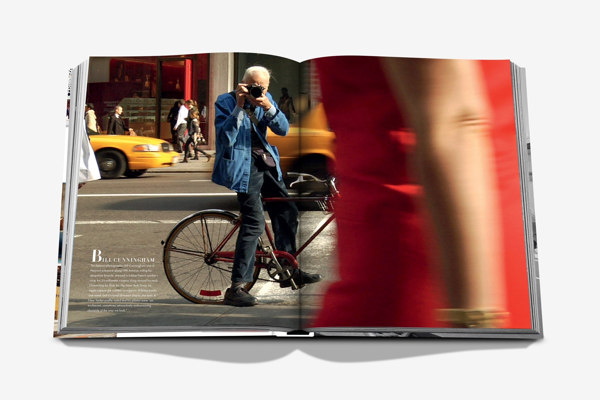 An open copy of Assouline’s "5th Avenue" displays an iconic street photo of a man taking a picture beside a bicycle, with a blurred figure and yellow taxis in the background.