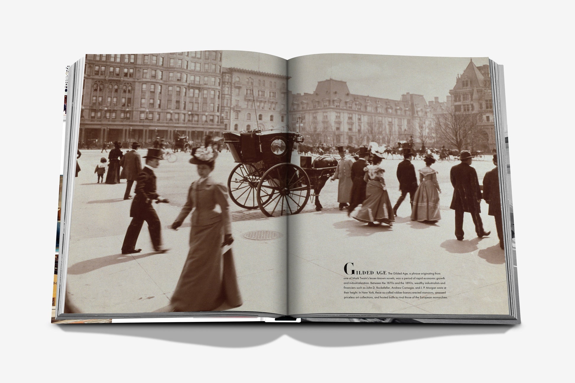 An open history book from Assouline titled "5th Avenue" shows a sepia photo of people in late 19th-century attire walking by a horse-drawn carriage, with historic buildings lining the iconic New York street.