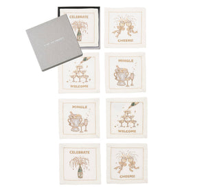 The Cheers Cocktail Napkin Set by Kim Seybert includes seven linen napkins with embroidered celebratory designs and text, arranged next to a gray box labeled "THE EMERSON." Ideal for festive gatherings.