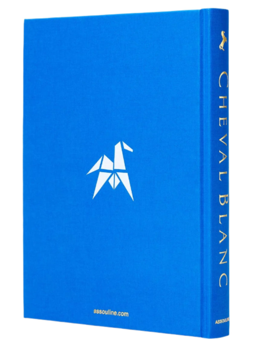Blue book titled "Cheval Blanc" by Assouline features a geometric horse logo on the front, symbolizing luxury hospitality, with the publisher's website at the bottom.