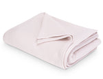 The Costa Mesa Blanket Collection by Matouk features a soft, light pink knitted blanket displayed on a white background.