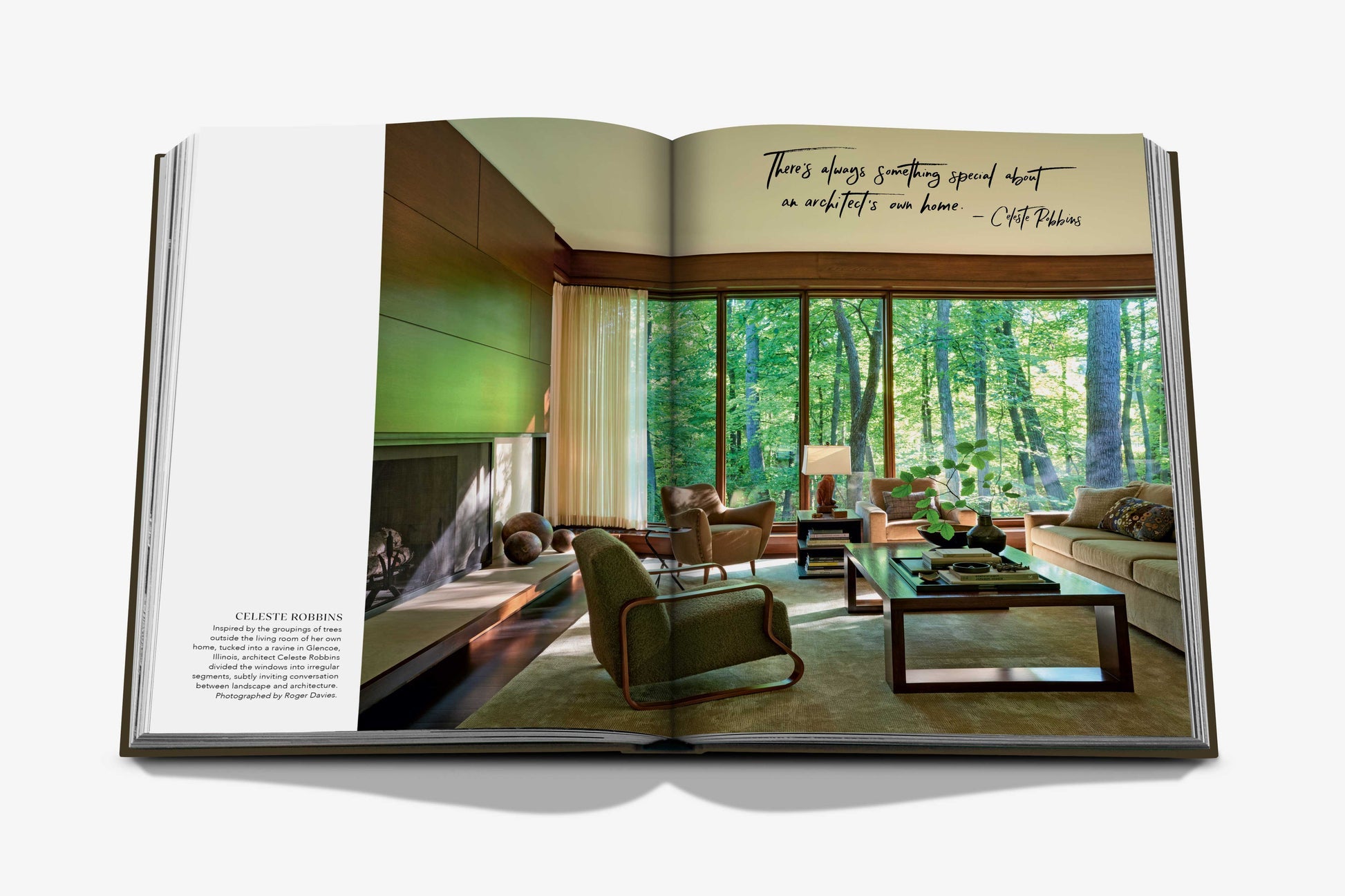 An open copy of Assouline’s "The Living Room" displays interior photography of a modern space with floor-to-ceiling windows, neutral furniture, and a fireplace. A handwritten quote about minimalism appears on the right page.