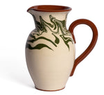 Handcrafted for the Sharland England Marbre Serveware Collection, this ceramic pitcher features a brown handle and rim, with green and brown marbled patterns swirling over a cream base.