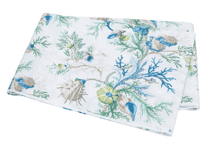 The Matouk Del Tesoro Bedding Collection, Sea, features folded fabric with a white background and a blue-green seaweed and seashell pattern, evoking an oceanic fantasy.