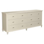 The Elena Double Chest by Tritter Feefer is a cream-colored dresser with six drawers, horizontal grooves, metal handles, and short tapered legs.
