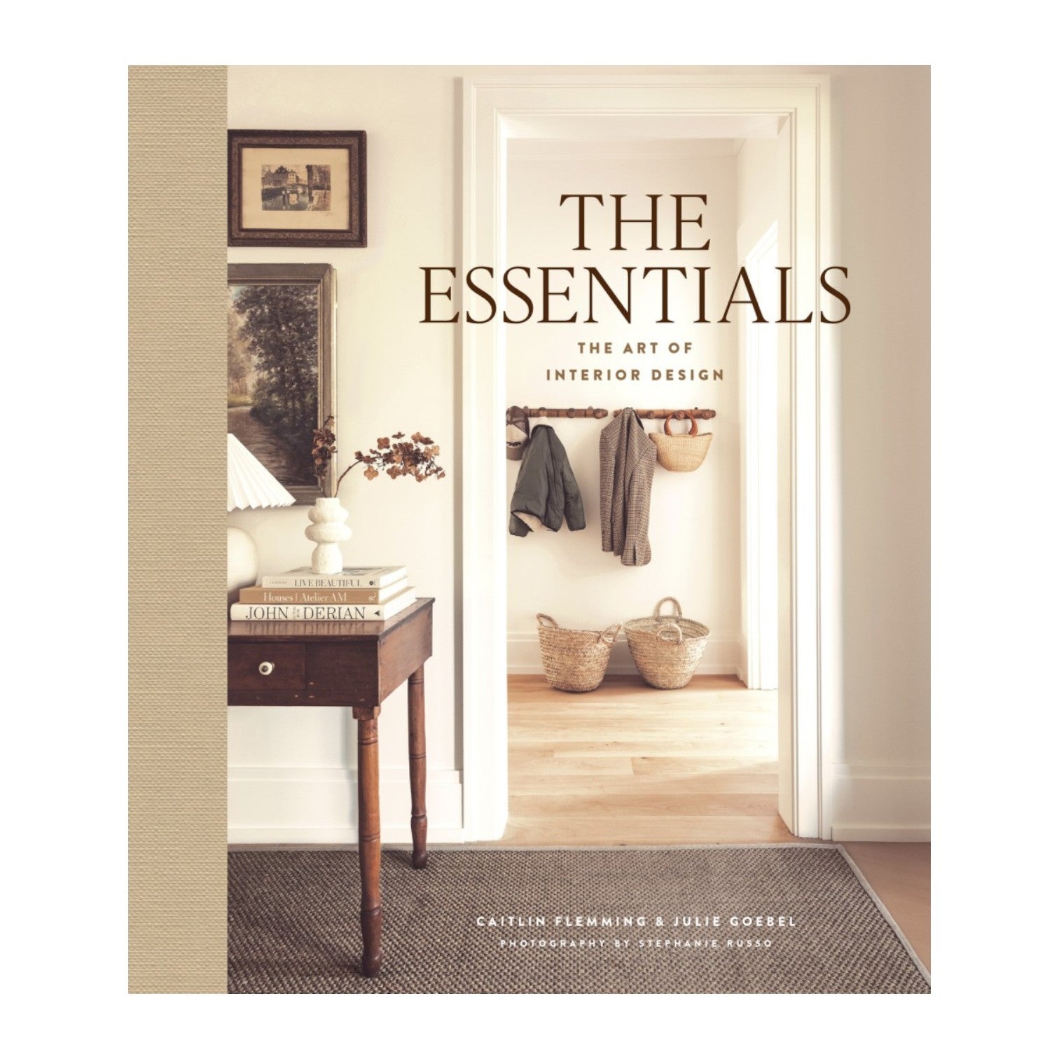 Abrams’ "The Essentials: The Art of Interior Design" features a stylish hallway scene with baskets, coats, and a side table—an inspiring book perfect for home decor enthusiasts.