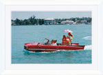 Getty Images’ “Sea Drive” by Slim Aarons, offered by Soicher Marin, shows a red amphibious car with six people gliding on water amid sunny buildings and trees, evoking luxury and classic style from 1967.