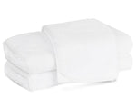 Three neatly folded white towels from the Matouk Giza Bath Collection, crafted from luxurious Egyptian cotton, are stacked on a plain white background.