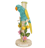 The El Pajaro Flower Vase by Mercedes Salazar features a colorful wicker parrot on a wrapped pole with yellow fruits, green leaves, and pink flowers atop a woven base, adding tropical style to your decor.