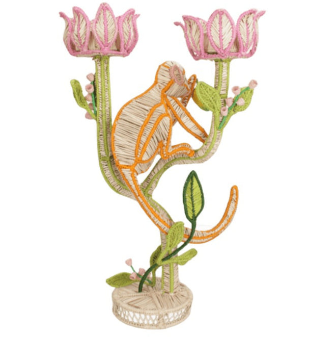 The El Mico Candle Holder by Mercedes Salazar features a whimsical woven monkey perched on a green and pink floral branch atop a round base, blending functional décor with playful charm for any room.