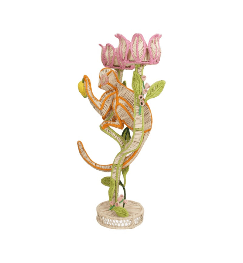 The El Mico Candle Holder by Mercedes Salazar is a colorful woven sculpture of a monkey climbing a vine with pink flowers, standing on a round base—offering whimsical, functional décor for your home.