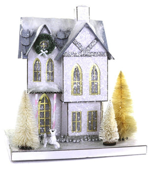 The Blue Mill House by Cody Foster features yellow windows, a wreath above the door, bottle brush trees, and a white polar bear figurine—miniature and perfectly sized to fit in its charming cardboard box.