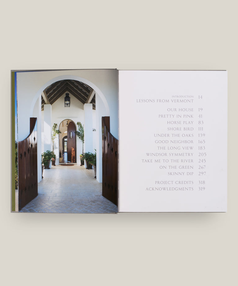 An open book, House Love: Moor Baker Architects by Vendome, displays a photo of a classical arched entryway on the left and a table of contents with chapter titles and page numbers on the right.