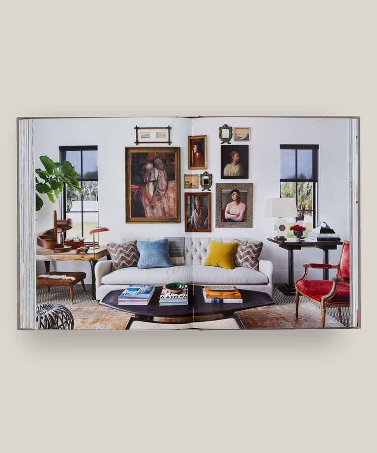 A modern living room with a white sofa, colorful pillows, coffee table, red chair, plant, and artwork—offering a fresh take inspired by House Love: Moor Baker Architects from Vendome.