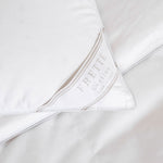 Close-up of a white Cortina Medium Density Pillow Insert by Frette, showing a corner with a Frette label.