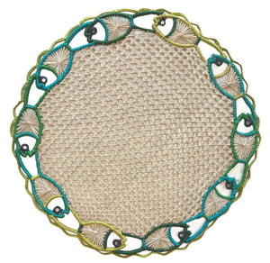 The Mercedes Salazar Fish Dance Placemat is a round woven placemat with an embroidered border of fish and seashell motifs in green, blue, and beige, bringing ocean-inspired color and style to your table.