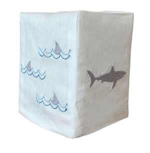 The Shark Bath Collection by Haute Home features a white Italian linen tissue box cover, hand-embroidered with shark fins on one side and a full shark silhouette on the other.