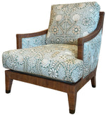 The St. Germain Lounge Chair by McGuire Furniture features a wooden frame and legs, with cushioned seat and back upholstered in light blue and white floral fabric, evoking classic French design for timeless elegance.
