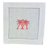 The Coastal Cocktail Napkin Set by Pink House Mustique features white linen napkins with embroidered pink palm trees at the center and a coastal-inspired hemstitch border.