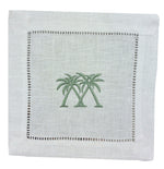 The Coastal Cocktail Napkin Set by Pink House Mustique features white linen napkins with two green palm trees embroidered in the center and a decorative openwork hem, adding a refined coastal touch.