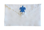 From the Pink House Mustique Linen Envelope Pouch Collection, this white scalloped pouch features coastal charm with a blue embroidered turtle and a button closure.