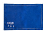 The Coastal Linen Placemat Set by Pink House Mustique features rectangular blue placemats with stitched edges and two white embroidered palm trees—ideal for bringing a beach-inspired touch to your dining space.