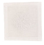 The Haute Home Sea Sponge Coaster Set features white fabric squares, hand embroidered with a coral-like design and stitched borders—perfect for pairing with napkins or using as an elegant set of 4 for sophisticated table settings.