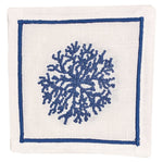 The Haute Home Sea Sponge Coaster Set features white linen coasters with a blue hand-embroidered coral motif at the center, outlined by a blue rectangular border.