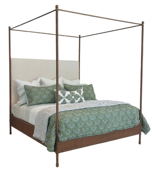 The Rita Cane Wrap Four Poster Bed by Julian Chichester features a beige headboard, bronze frame, and green, white, and patterned bedding with multiple pillows for an inviting Adnet-inspired look.