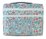 The Walton Travel Case by Walker Valentine is a rectangular organizer with a floral pattern and "STUFF" in bold on the front. Double zippers open to spacious compartments for essentials.