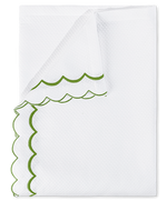 A folded white diamond pique napkin from the Matouk India Pique Bedding Collection in Grass, featuring green double-scallop embroidery along the textured edges.