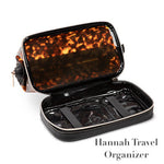The Stephanie Johnson Miami Tortoise Travel Collection features a rectangular organizer with a zip opening, faux-leather trim, tortoiseshell-patterned top, clear pockets, and elastic straps.