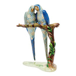 The Herend Reserve Collection Pair of Macaws is a limited edition porcelain figurine featuring two blue and white parrots perched together on a leafy branch, set on a white base.