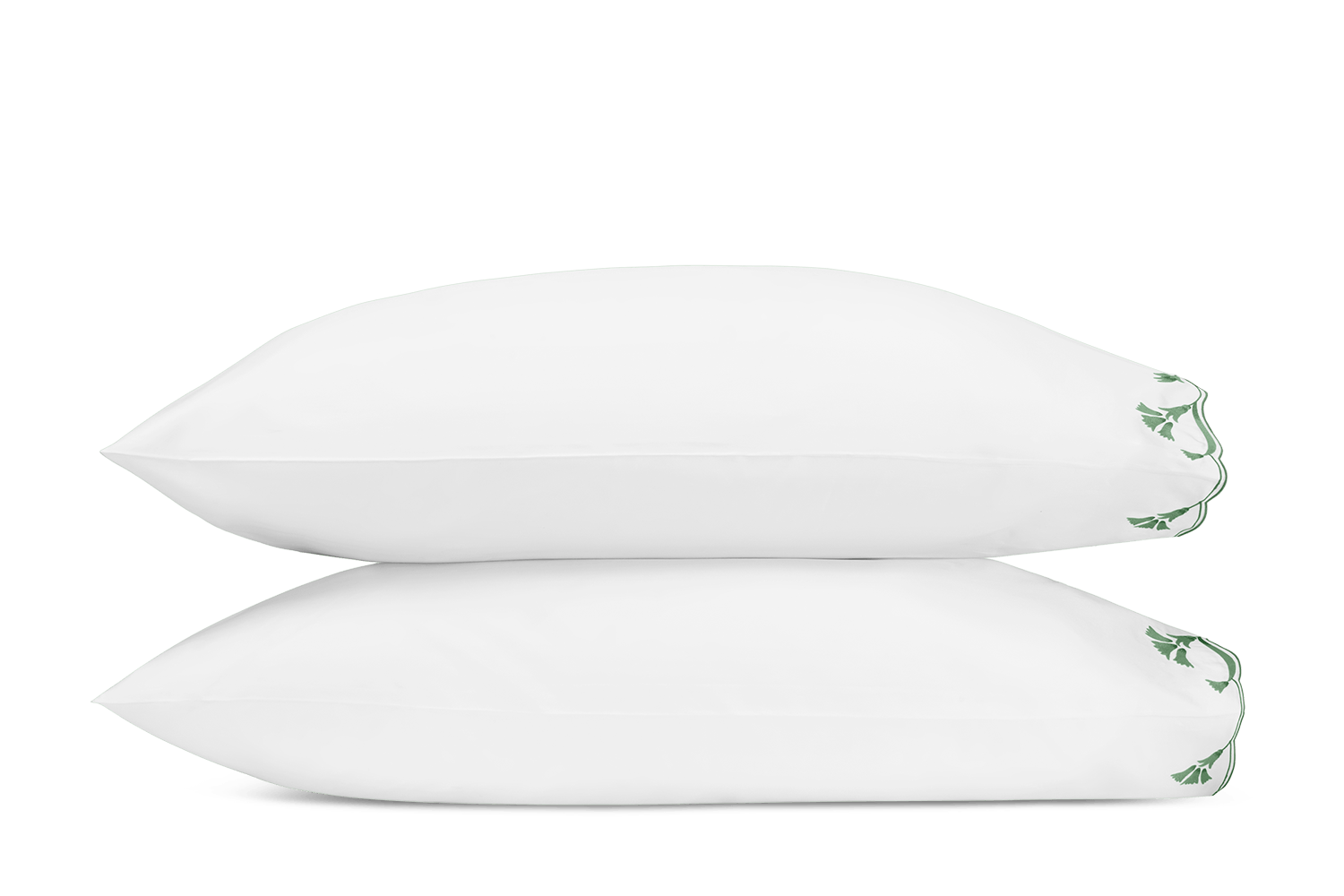 Two white pillows from the Matouk Marcella Bedding Collection, Clover, with green leaf embroidery on the edges, are stacked against a plain white background—an elegant addition to any embroidered bedding set.