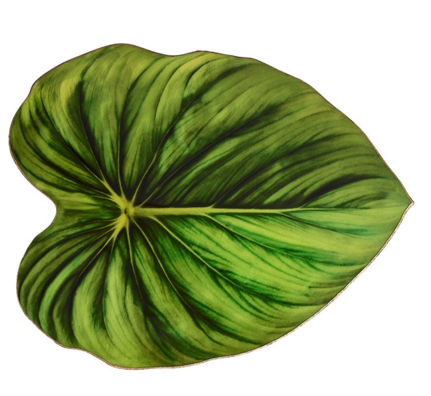 The Kim Seybert Tropicana Placemat features a single large green tropical leaf with striking veins on a crisp white background, adding elegance to any table setting.