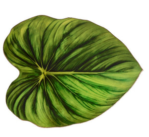 The Kim Seybert Tropicana Placemat features a single large green tropical leaf with striking veins on a crisp white background, adding elegance to any table setting.