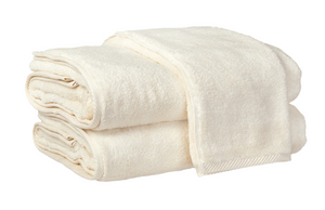 Two neatly folded, absorbent Matouk Milagro Bath Collection towels in ivory are stacked on top of each other against a white background.
