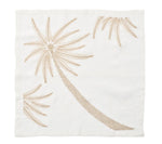 The Kim Seybert Palm Coast Napkin Set features white napkins embroidered with palm fronds and palm trees in light brown, perfect for a coastal dining table.