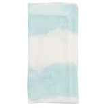 The Kim Seybert Watercolor Stripe Napkin Set features folded linen napkins in a light blue and white tie-dye pattern, displayed on a white background.