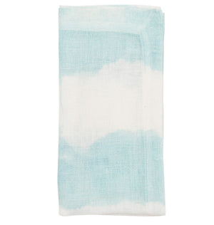 The Kim Seybert Watercolor Stripe Napkin Set features folded linen napkins in a light blue and white tie-dye pattern, displayed on a white background.