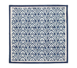 The Alfresco Napkin Set by Kim Seybert features a dark blue and white geometric pattern inspired by block printing, with repeating diamond shapes, stylized floral designs, and a solid blue border.