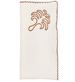The Kim Seybert Royal Palm Napkin Set features white napkins with hand-embroidered edges and a brown abstract tropical tree leaf design in the corner.